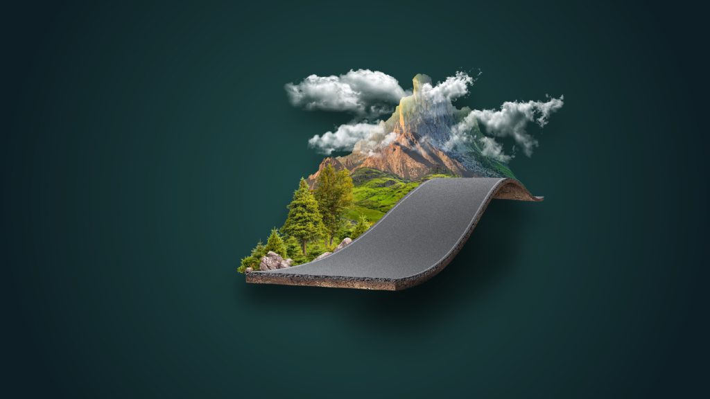 Dağ ve ormanın arasından geçen kıvrımlı bir asfalt yol.