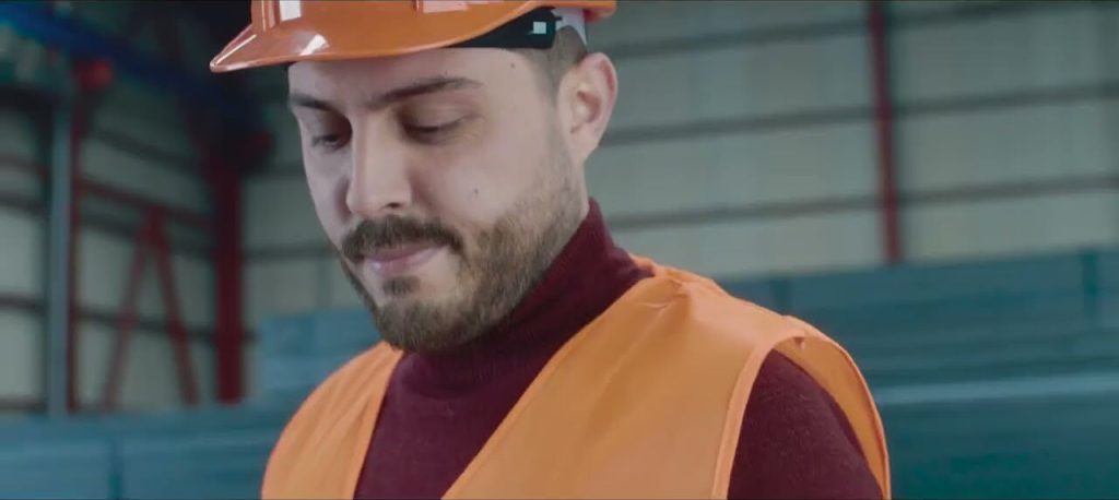 Proemtia lansman filminden bir kare: depoda, turuncu baret ve yelek giymiş bir çalışan aşağıya bakıyor.