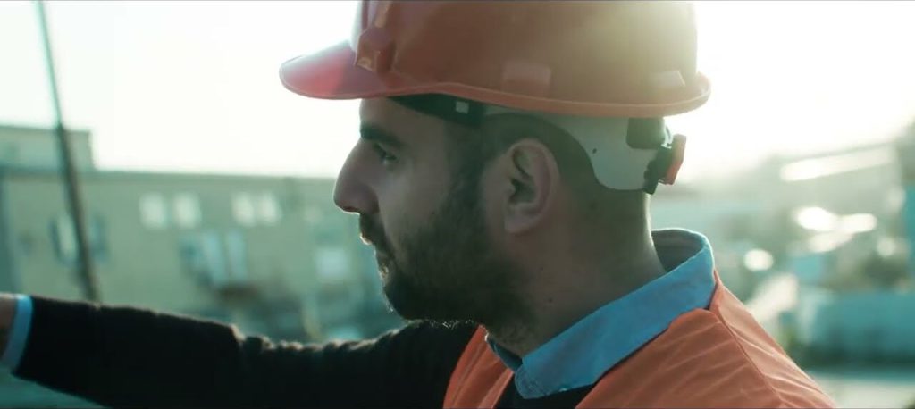 Proemtia lansman filminden bir kare: açık sahada, arka ışıkta turuncu baretli bir çalışan.