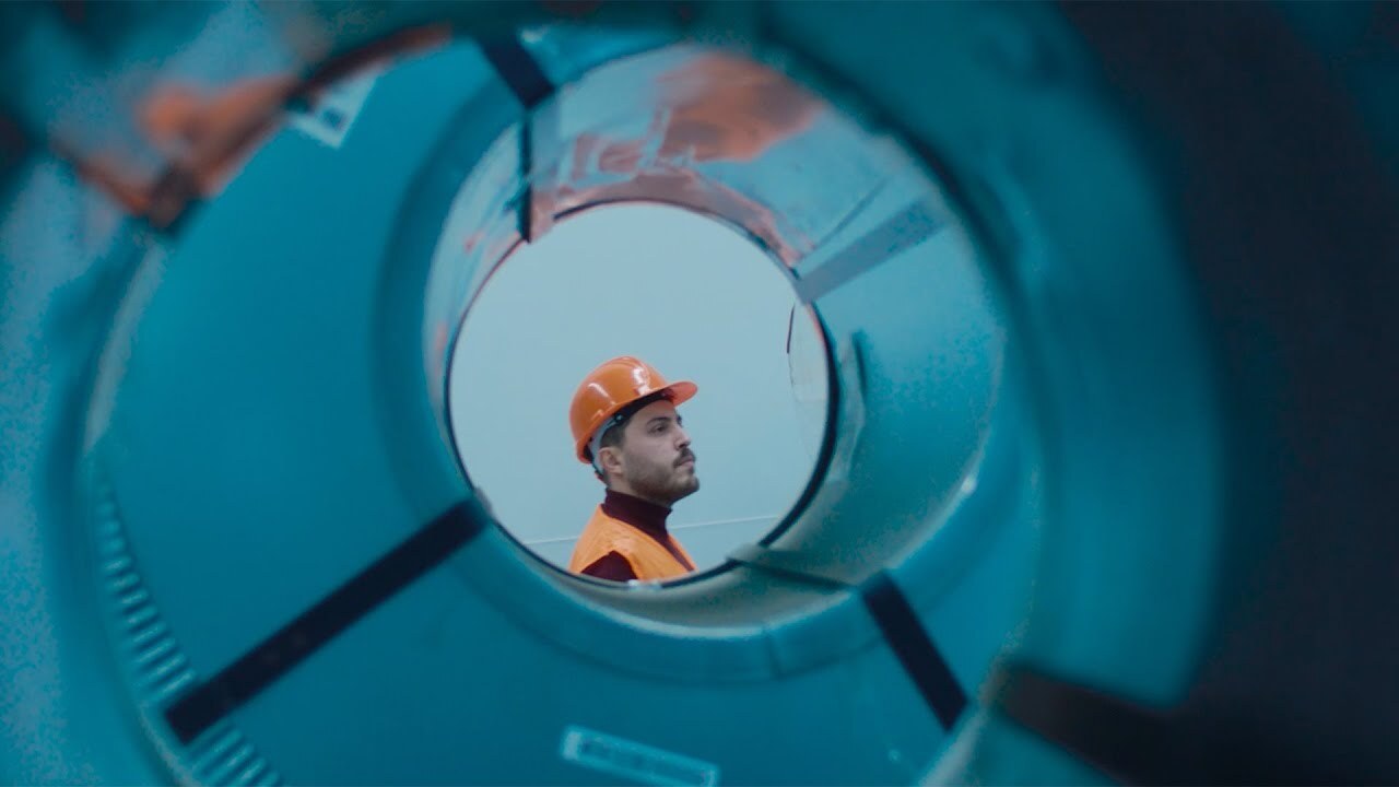 Proemtia lansman filminden bir kare: çelik bir rulonun içinden görünen, turuncu baretli ve yelekli bir çalışan.